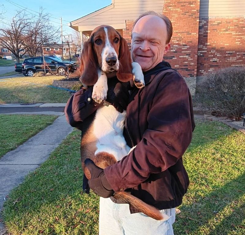 Brian J. Pollard holding his basset hound, Hero Henry, on a sunny afternoon